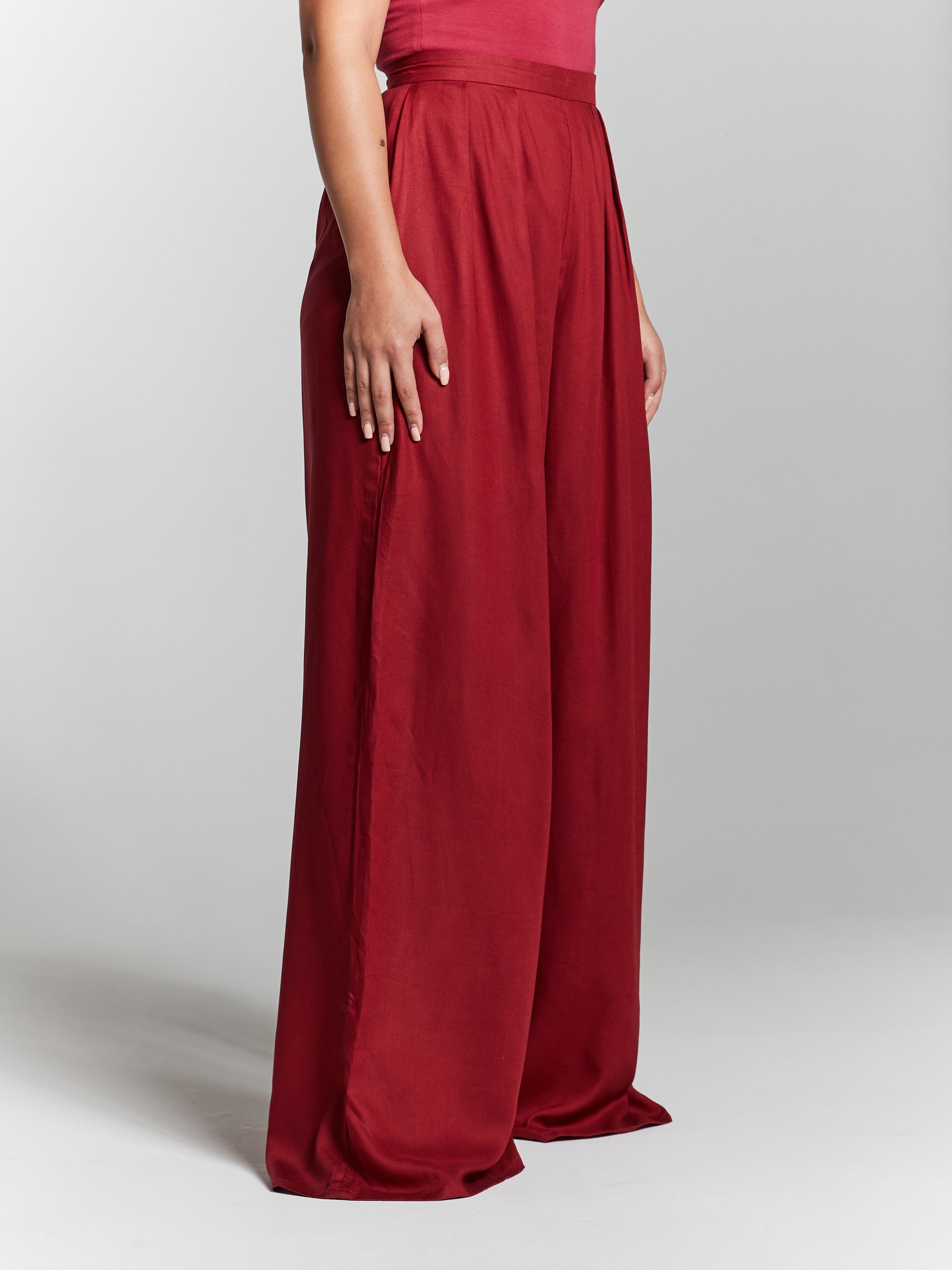 Ladies high rise recycled viscose pressed pleat wide leg trousers from British fashion label InFlair. Available in leg lengths petite 42" standard 44" tall 46" and available colours red maroon burgundy ivory white black green olive green. Designed to be a versatile addition to your closet, these maroon flares pair beautifully with a range of tops and accessories. From a tailored blouse for a polished look to a simple tee for a relaxed vibe, they are perfect for various occasions.